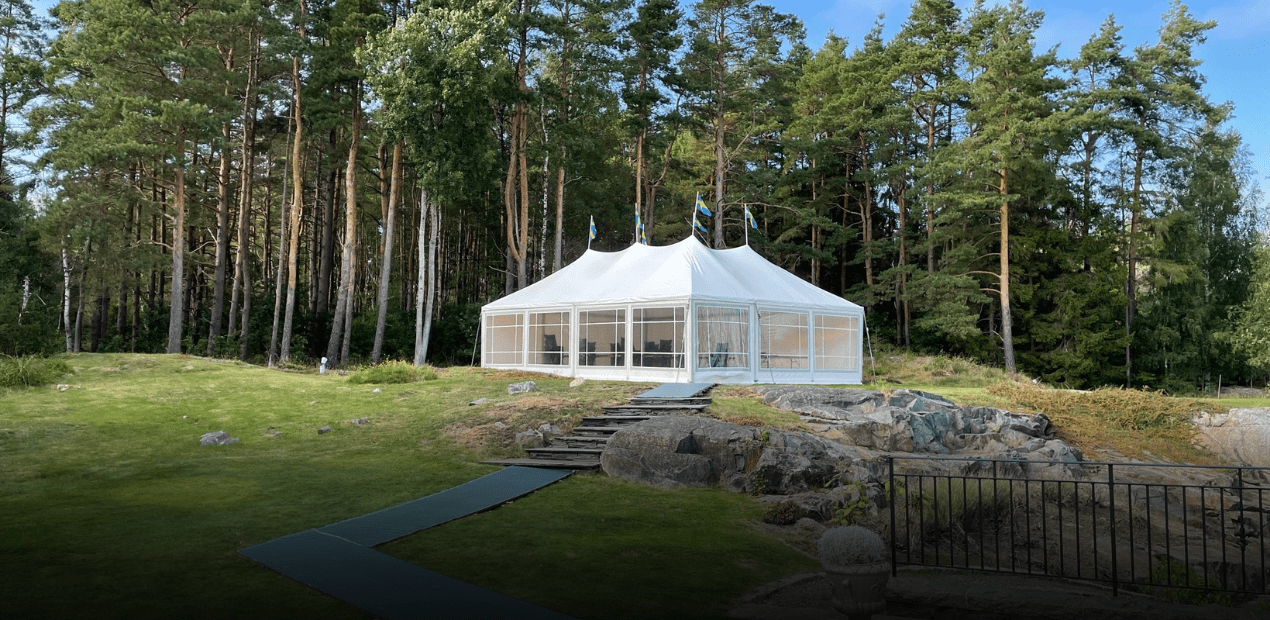 White tent set up outdoors with trees and rocks in the background